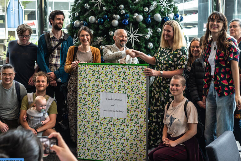 Members of Common Grace Aotearoa and advocates for better power company rules give a giant Xmas card to Electricity Authority CEO Sarah Gillies. Members of Common Grace Aotearoa and advocates for better power company rules give a giant Xmas card to Electricity Authority CEO Sarah Gillies.